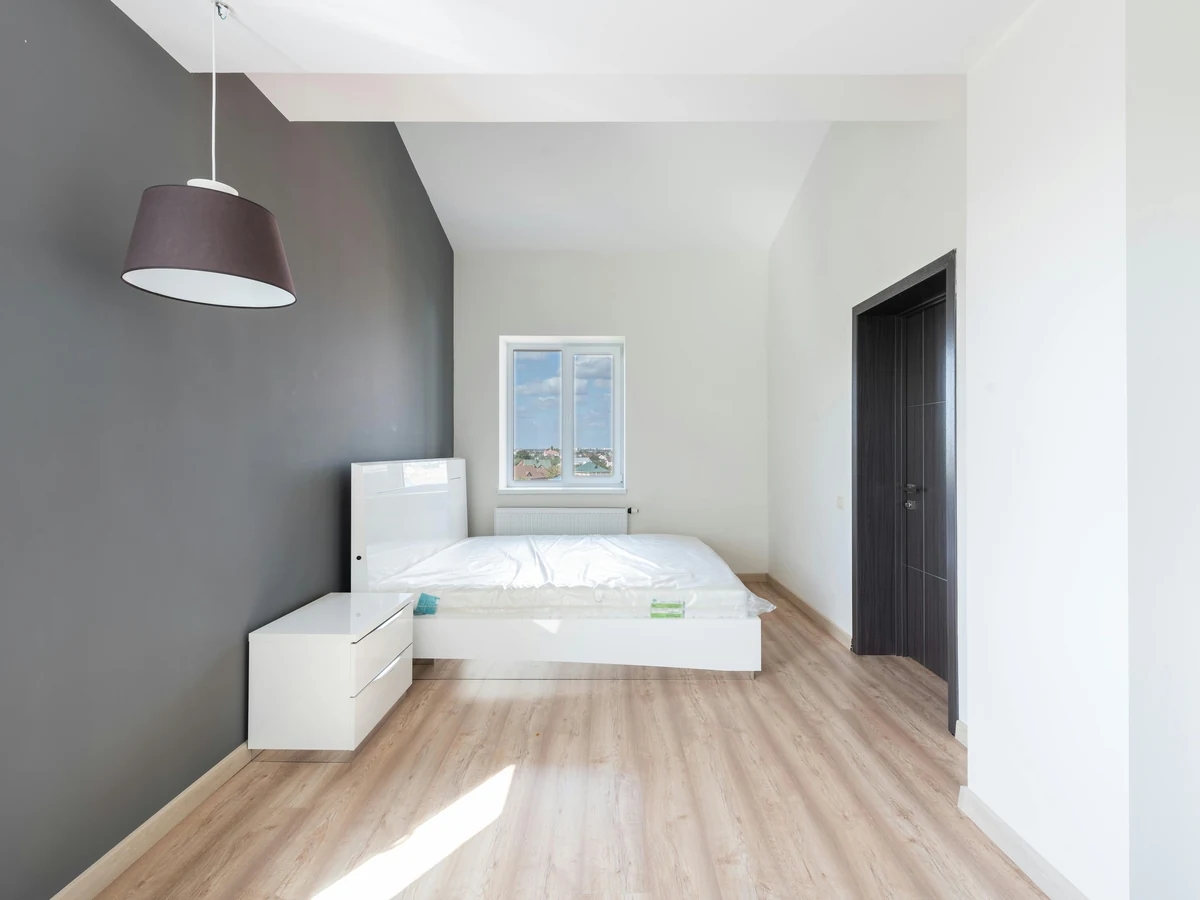 An empty bedroom with a dark grey feature wall and light wood flooring, ready for the next tenant