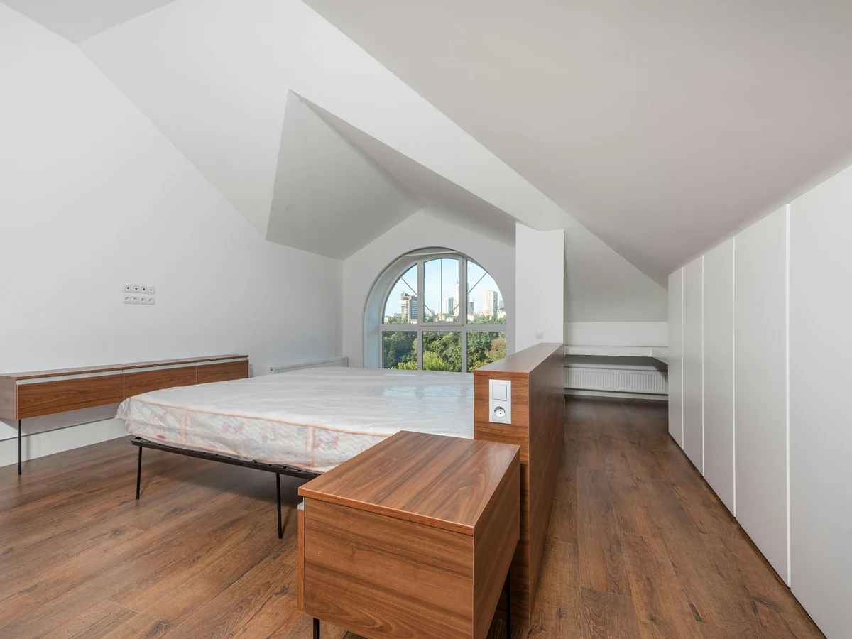 An empty loft bedroom with painted walls and wood flooring
