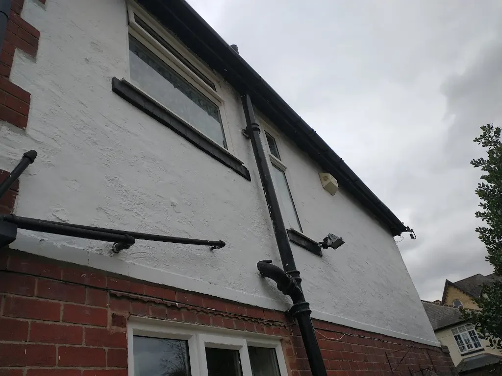 Fresh white masonry paint and black exterior trim on a house, completed by Altrincham Decorators.