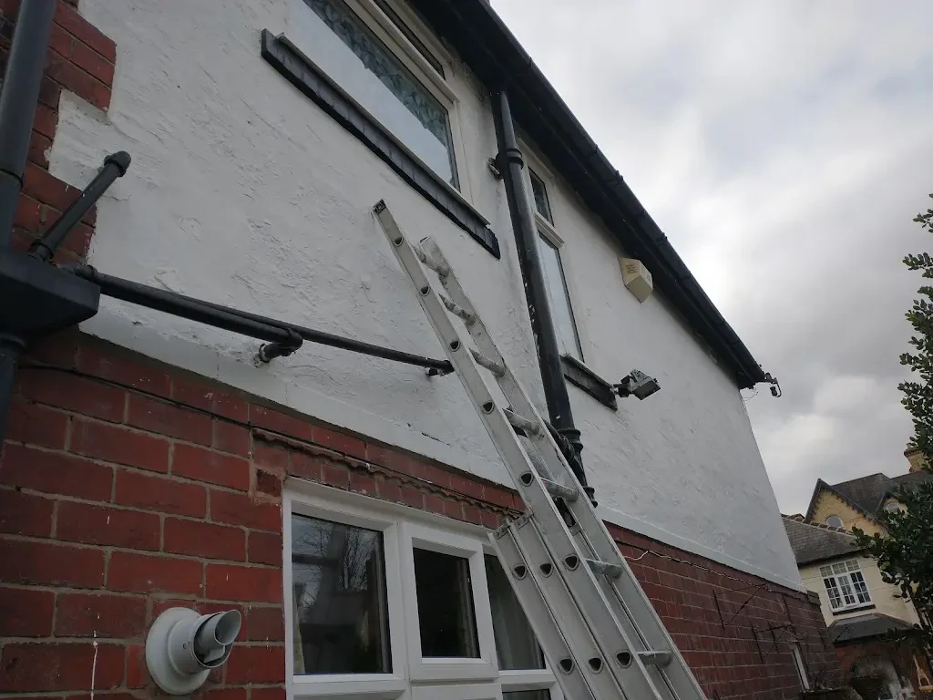 Repainted exterior wall with clean white masonry and black details by Altrincham Decorators.