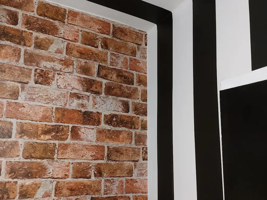 Brick-effect feature wall framed by black and white stripes, decorated by Altrincham Decorators.