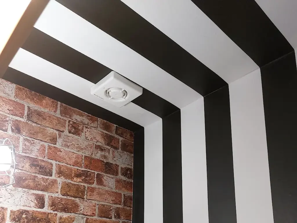 Black and white striped hallway leading to a brick-effect feature wall, decorated by Altrincham Decorators.