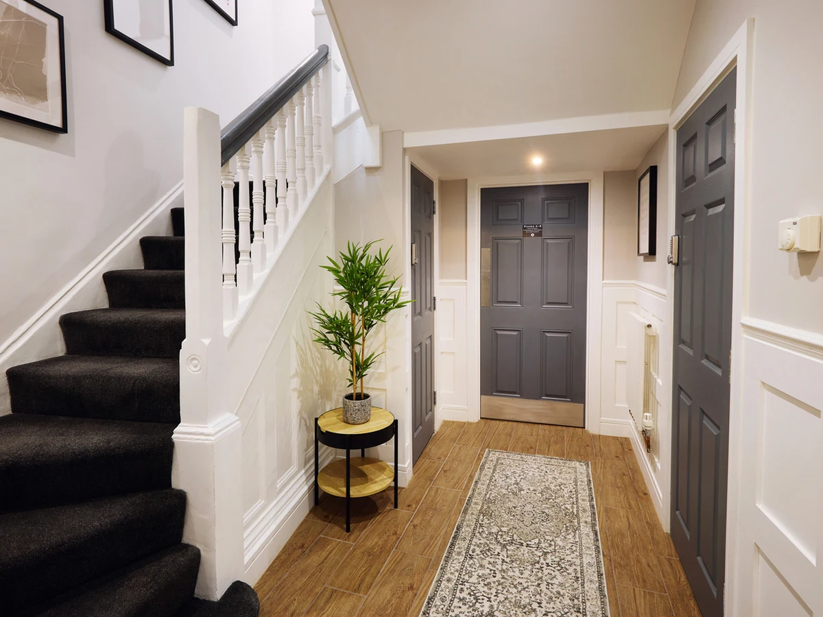 A hallway with a painted staircase and dark grey doors