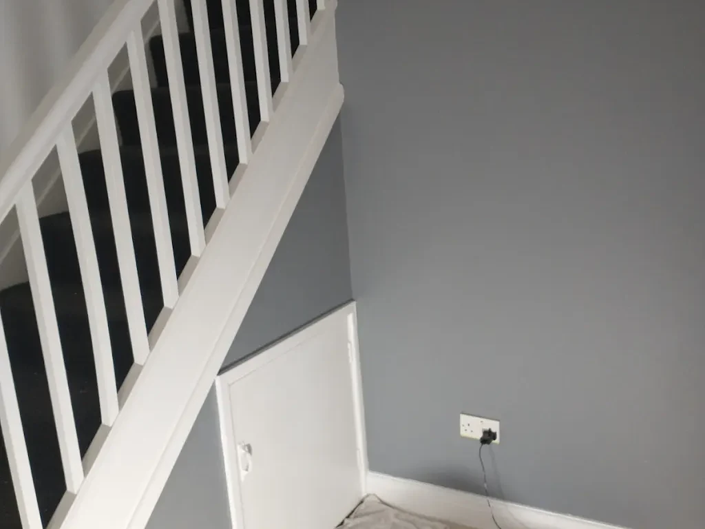 Grey under-stairs wall and white staircase woodwork painted by Altrincham Decorators.
