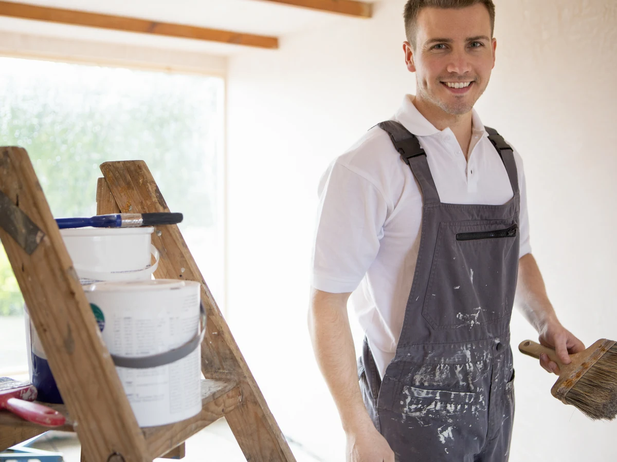 painting-decorating-decorator-brush-ladder-altrincham-decorators Professional decorator painting door with brush on ladder in Altrincham