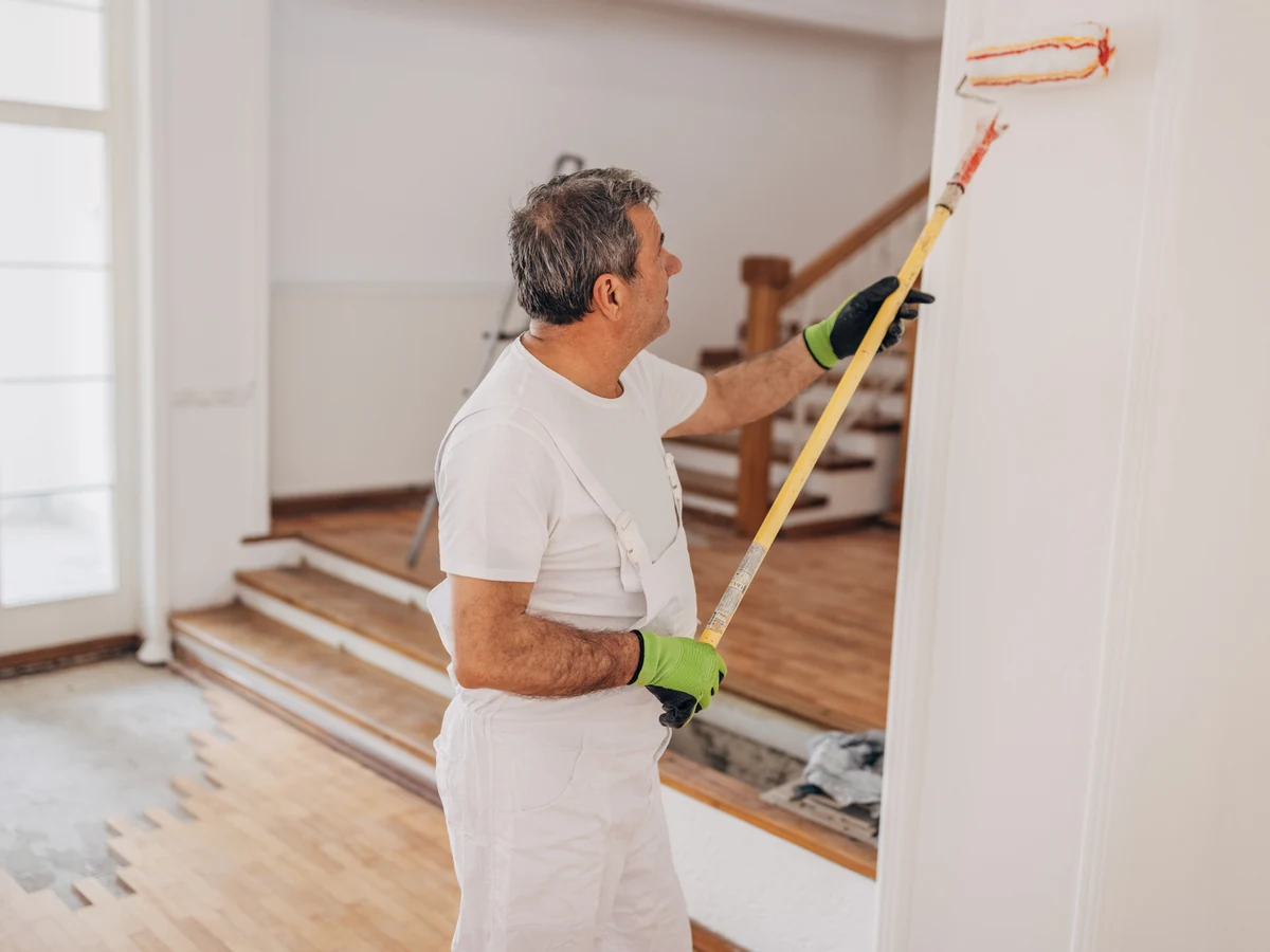 painting-decorating-mature-painter-rolling-altrincham-decorators Professional painter rolling interior walls in an Altrincham property