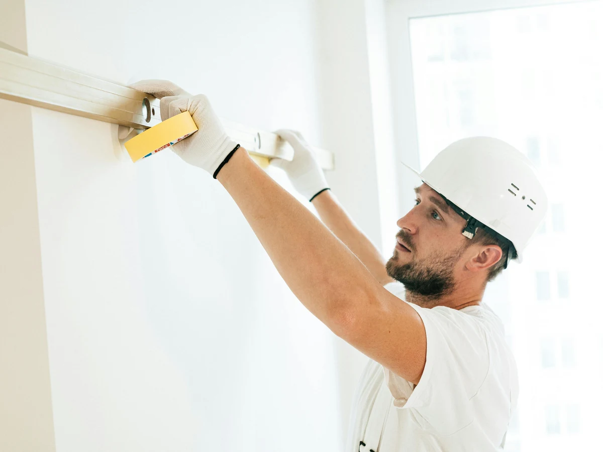 Decorator sanding ceiling surface before painting in Altrincham