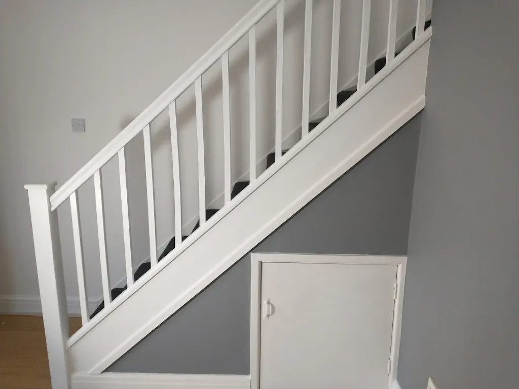Painted staircase with white spindles, grey walls and under-stairs storage by Altrincham Decorators.