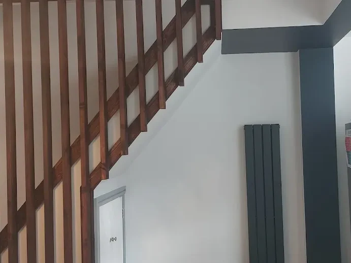 Redecorated staircase and kitchen area with white walls and dark trim by Altrincham Decorators.