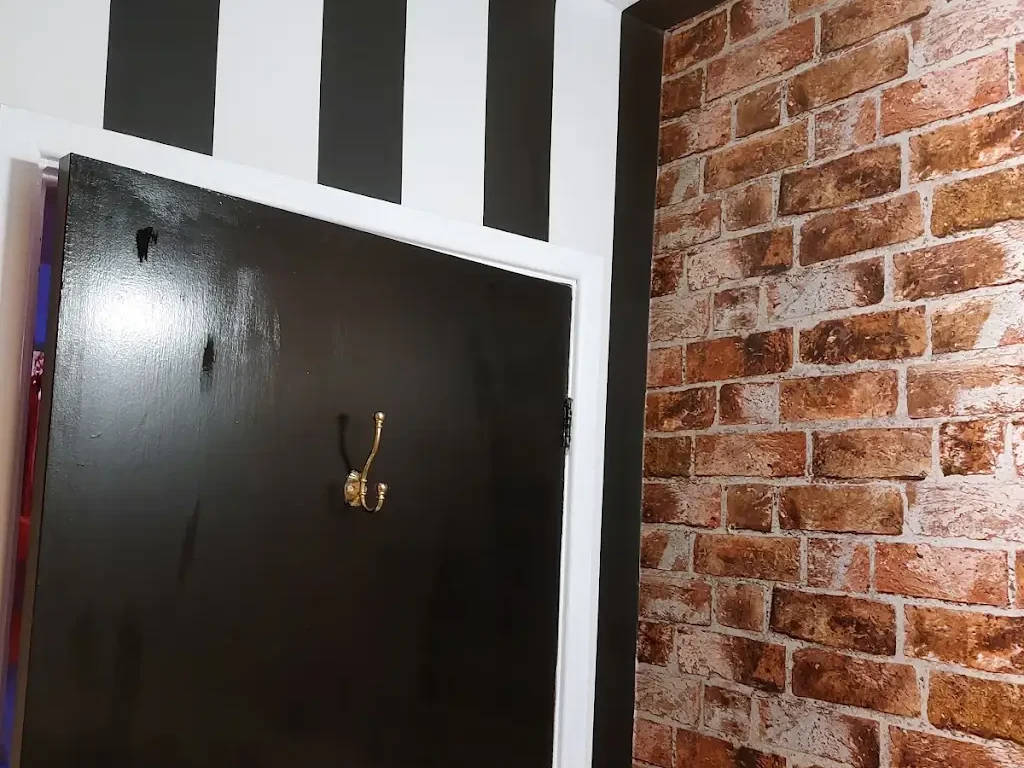 Black and white striped entrance hall with brick-effect wallpaper by Altrincham Decorators.